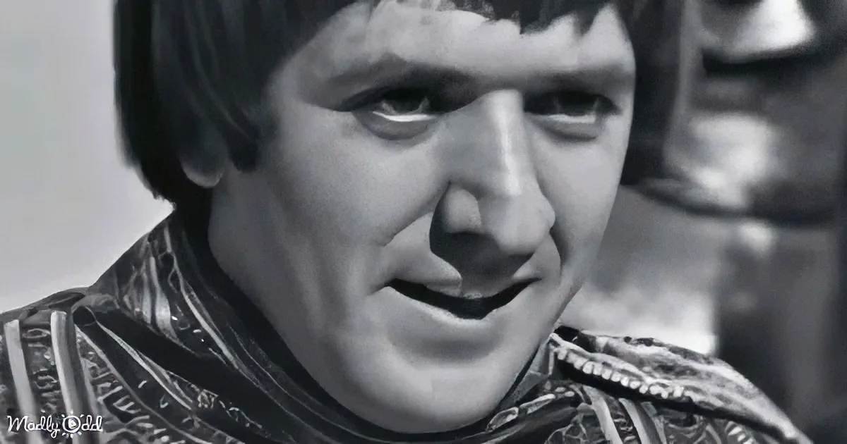 A person with dark hair and a patterned garment, possibly from a historical or theatrical setting.