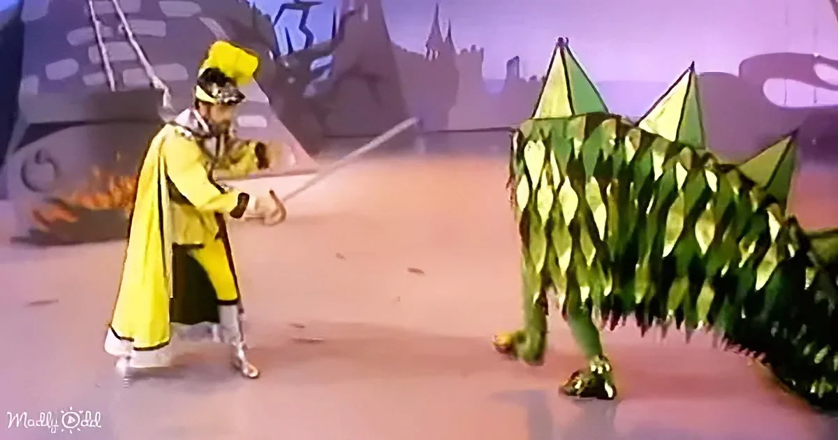 A character in a yellow costume wields a staff, facing a green, leafy creature in a fantasy setting.