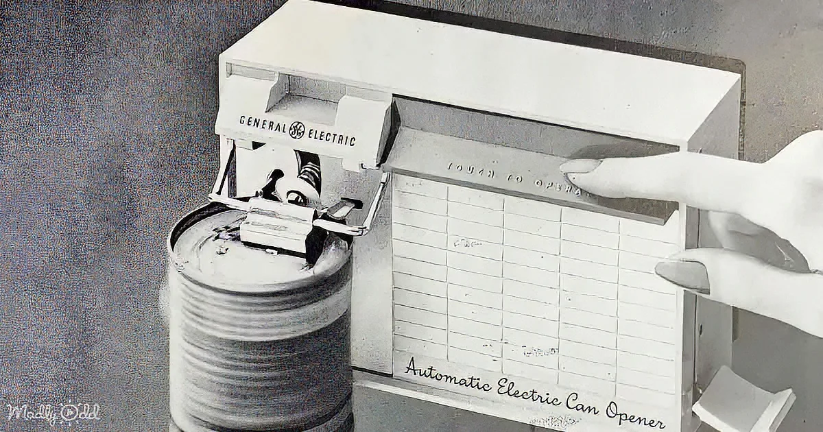 A vintage General Electric automatic electric can opener is shown in use, with a hand pressing a button.