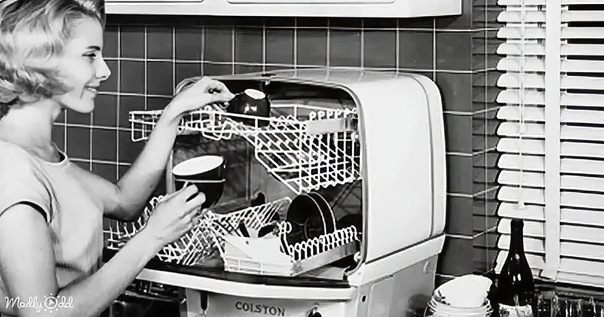 A woman is placing dishes into a vintage Colston dishwasher in a kitchen setting.