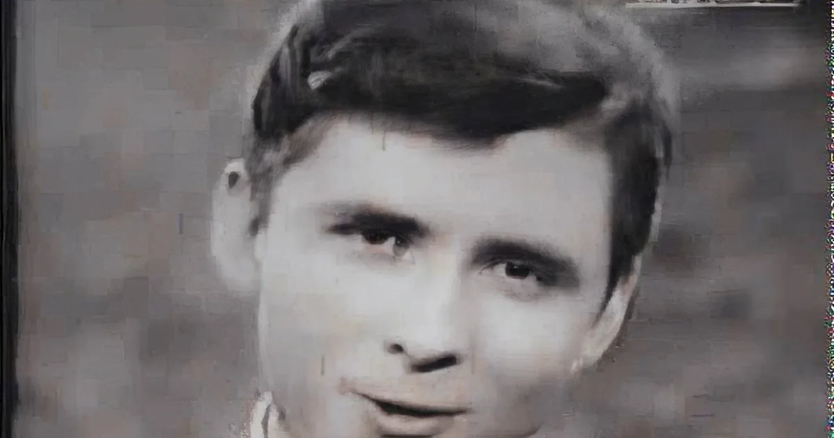 A smiling man with short dark hair, wearing a suit and tie, in a black and white photo.