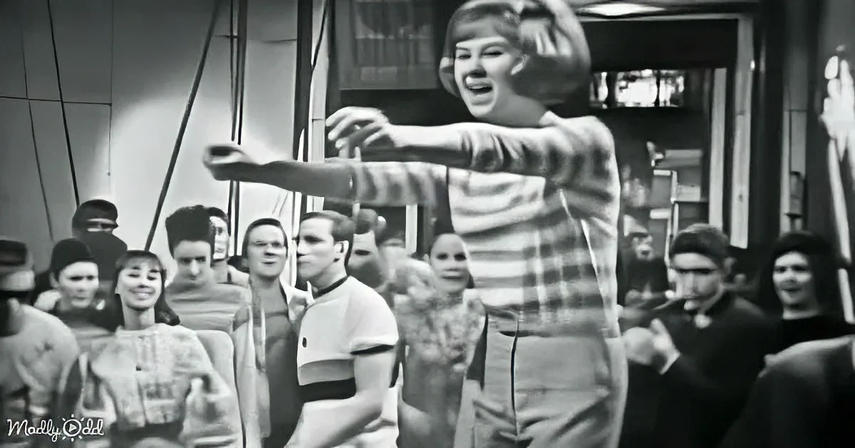 A person in a striped shirt is dancing energetically in front of a crowd, creating a dynamic scene.