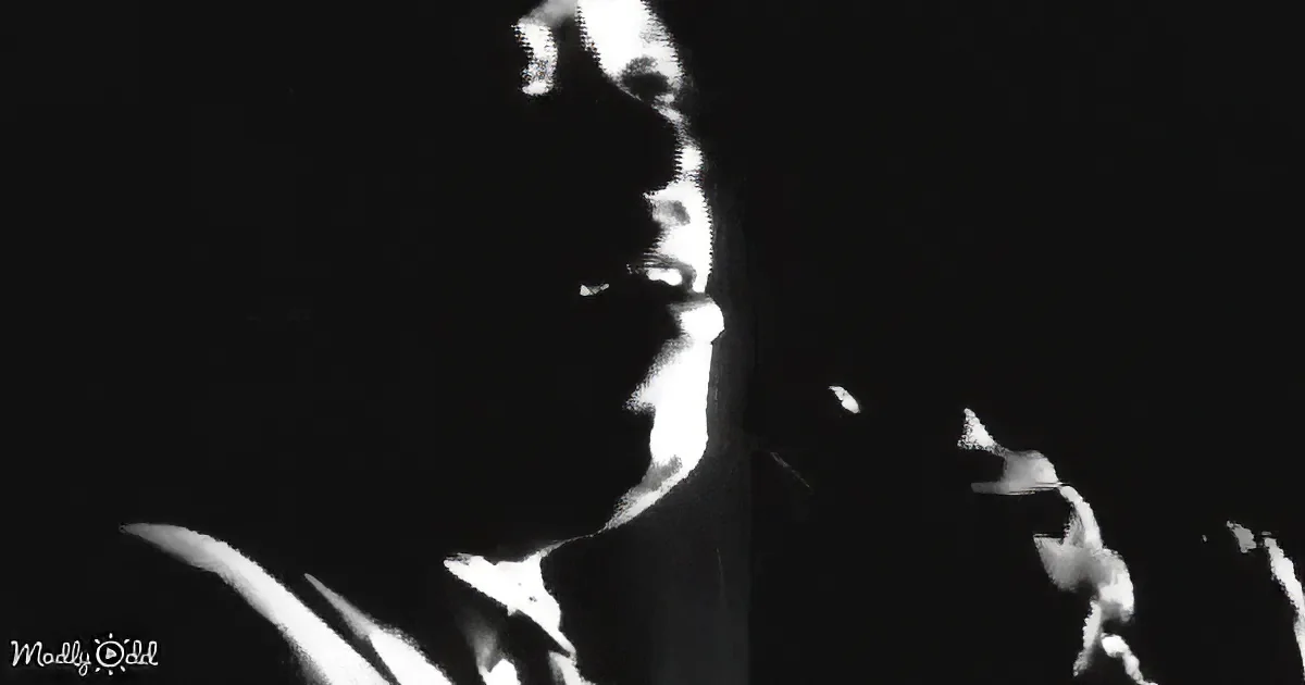 A silhouette of a person holding a microphone, possibly singing, against a dark background.
