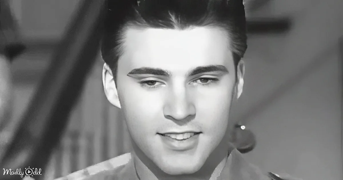 A smiling man with slicked-back hair and a military-style uniform.