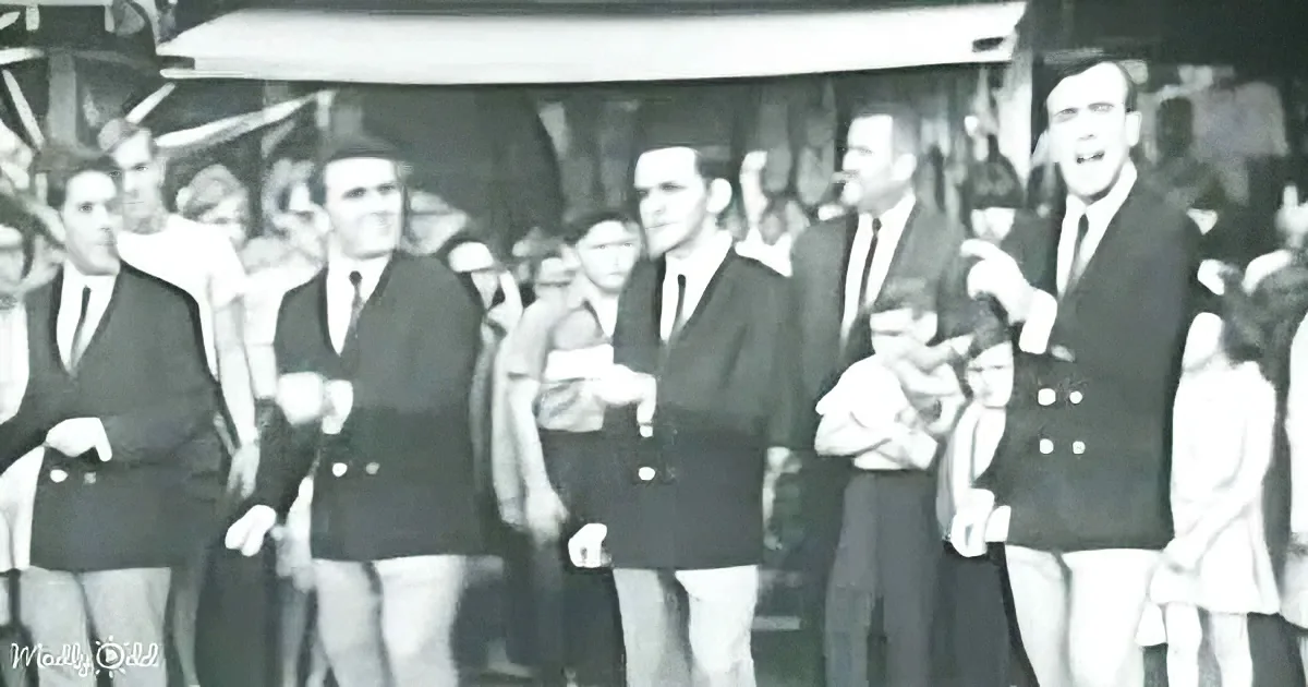 A group of men in suits and ties stands together, smiling and posing for a photo.