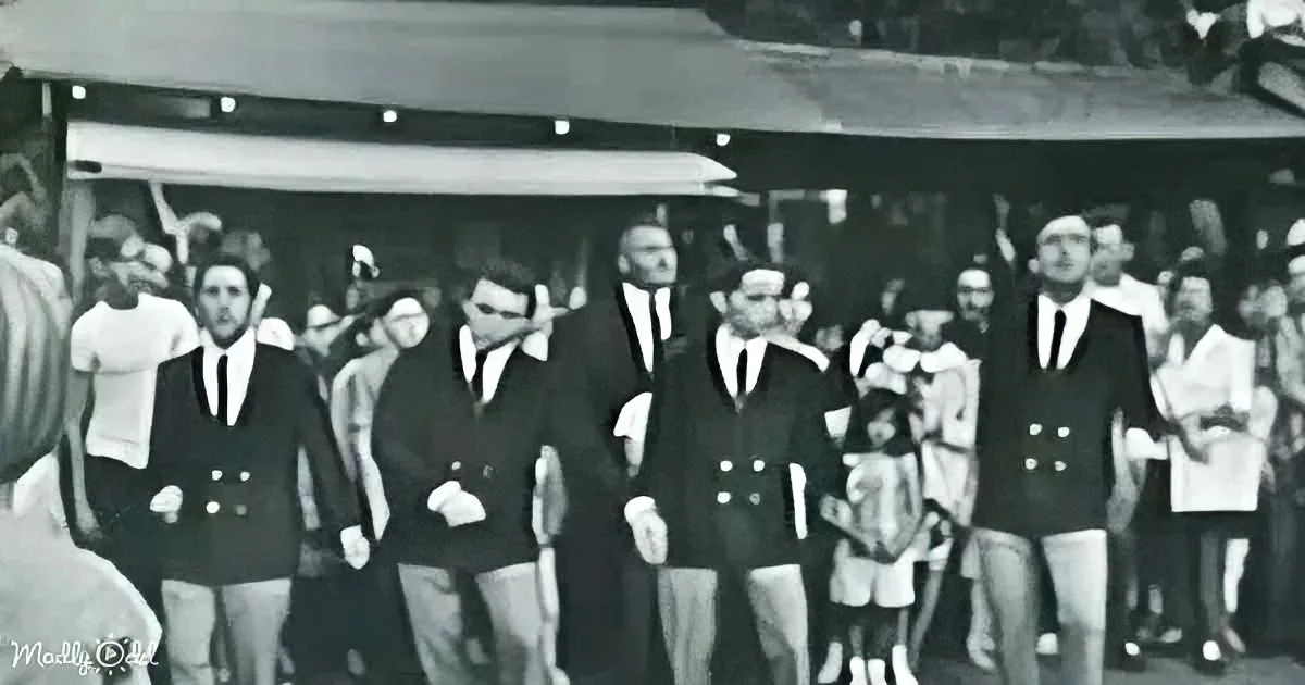Men in suits and ties stand in a line, possibly at a formal event or ceremony.