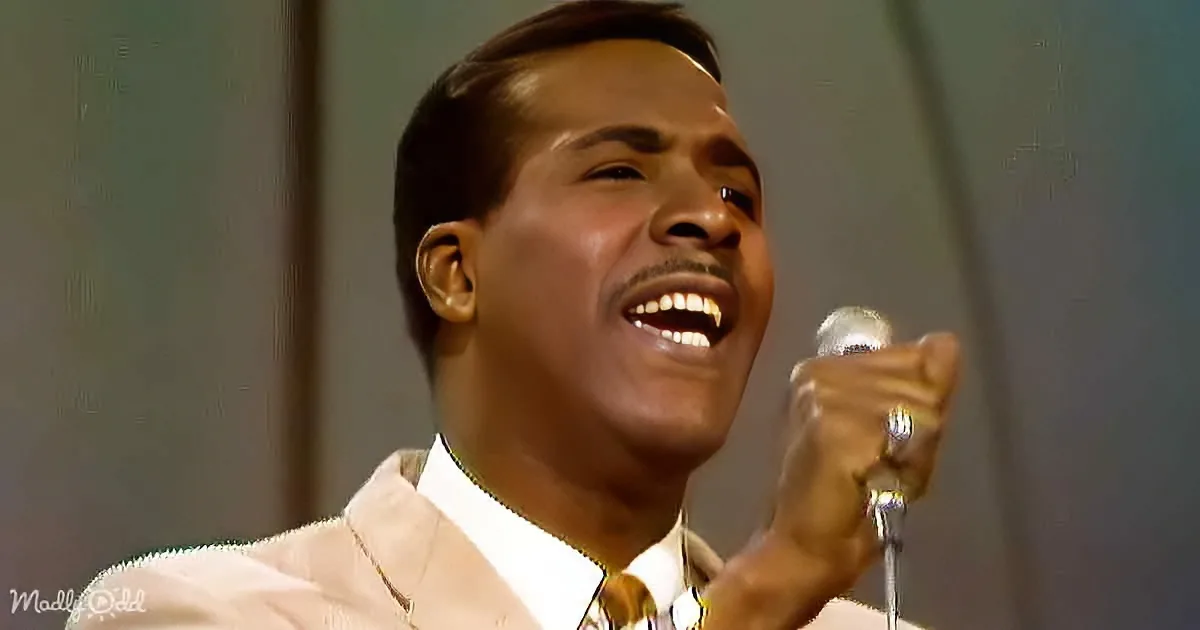 A man in a white suit sings passionately into a microphone, his eyes closed in emotion.