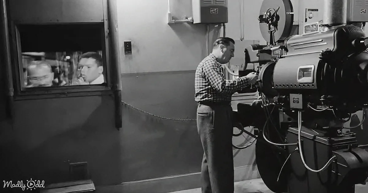 A man in a plaid shirt operates a large machine, with another person visible through a window in the background.