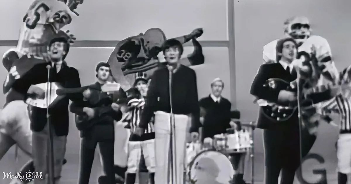 The Beatles perform the national anthem at a football game, with players and a band in the background.
