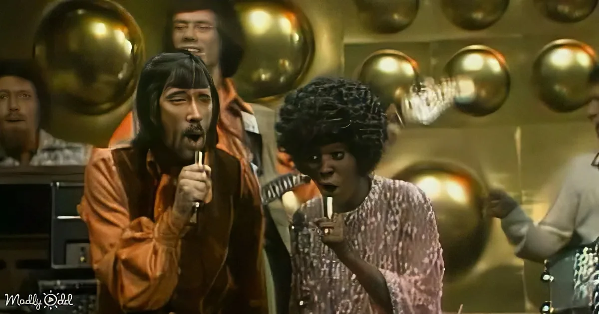 A man with a microphone sings passionately, surrounded by golden balloons and a band.
