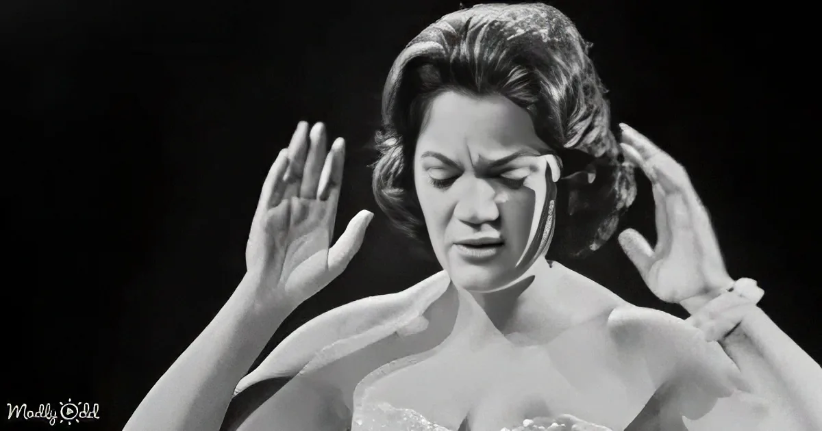 A woman in a white dress with her hands raised, appearing distressed or overwhelmed.