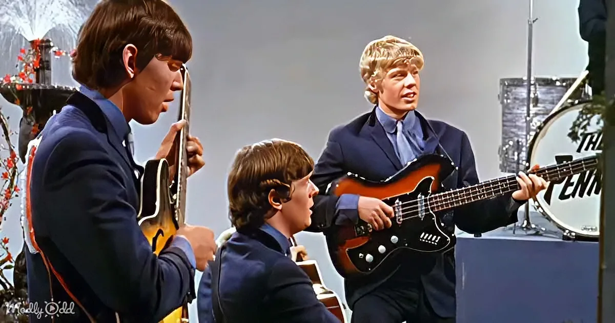 A man in a suit plays a guitar while another in a suit sings into a microphone.