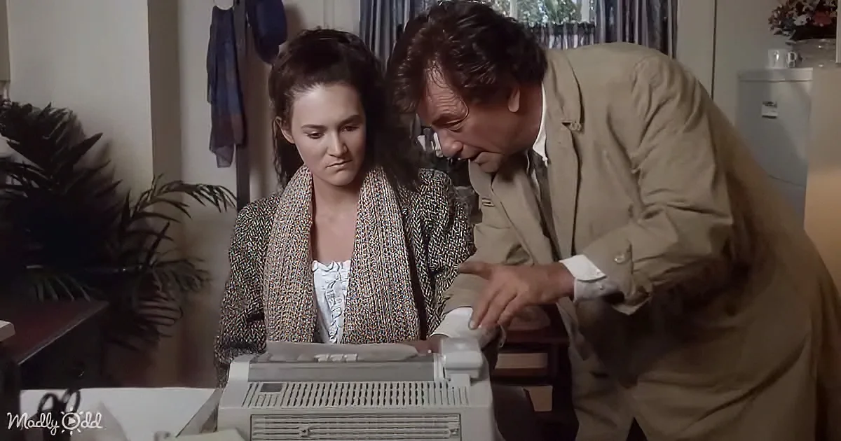 A man leans over a woman using a vintage computer in a home setting.