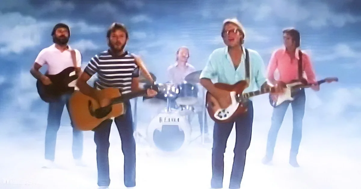 A band of four musicians playing guitars and drums against a bright, cloudy sky backdrop.
