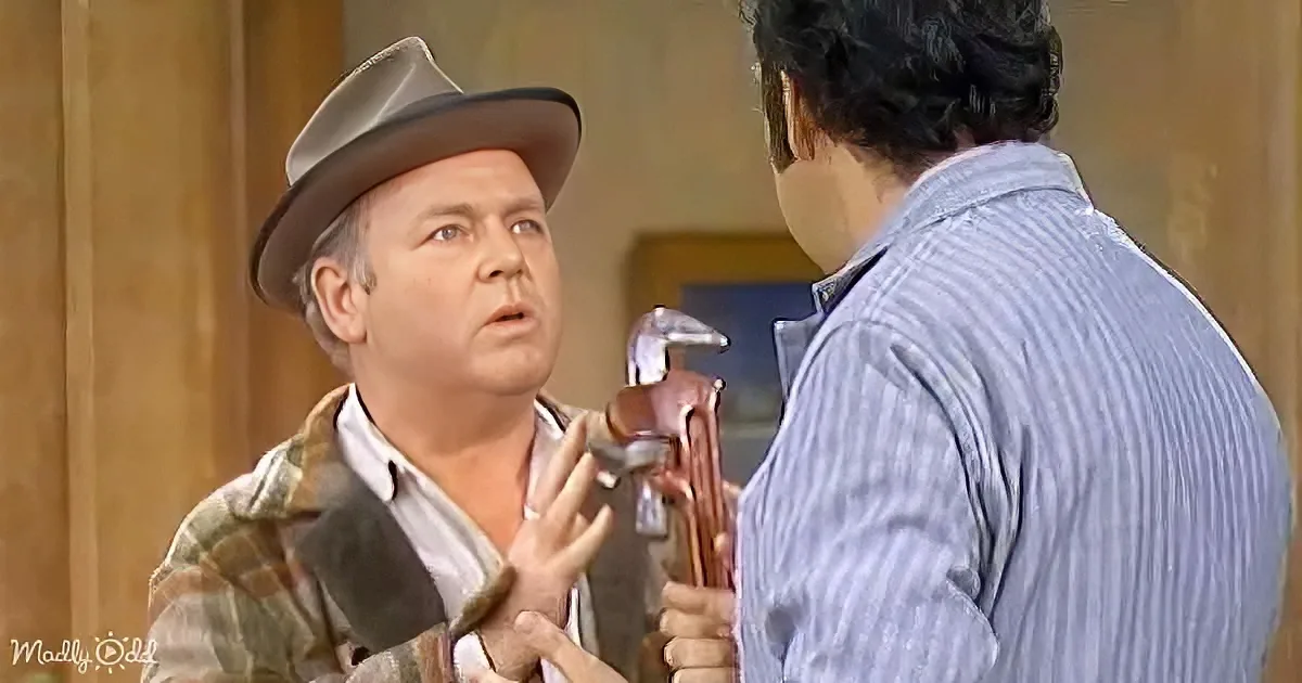 A man in a hat holds a hammer, gesturing while talking to another man in a striped shirt.