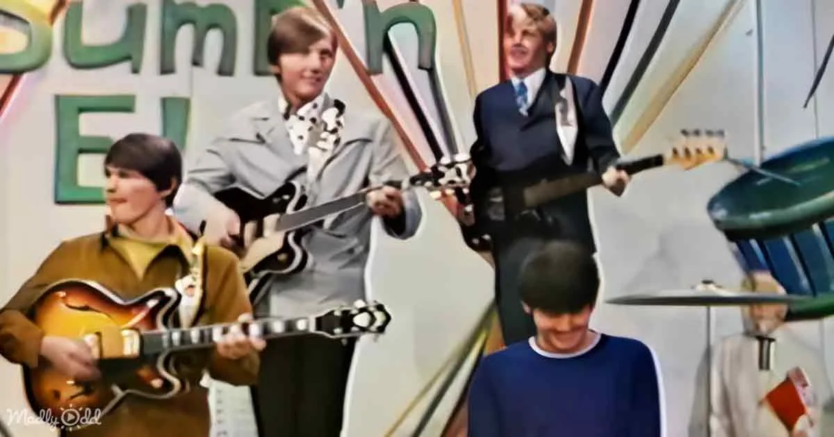 A group of musicians, including a guitarist and a drummer, are performing on stage.
