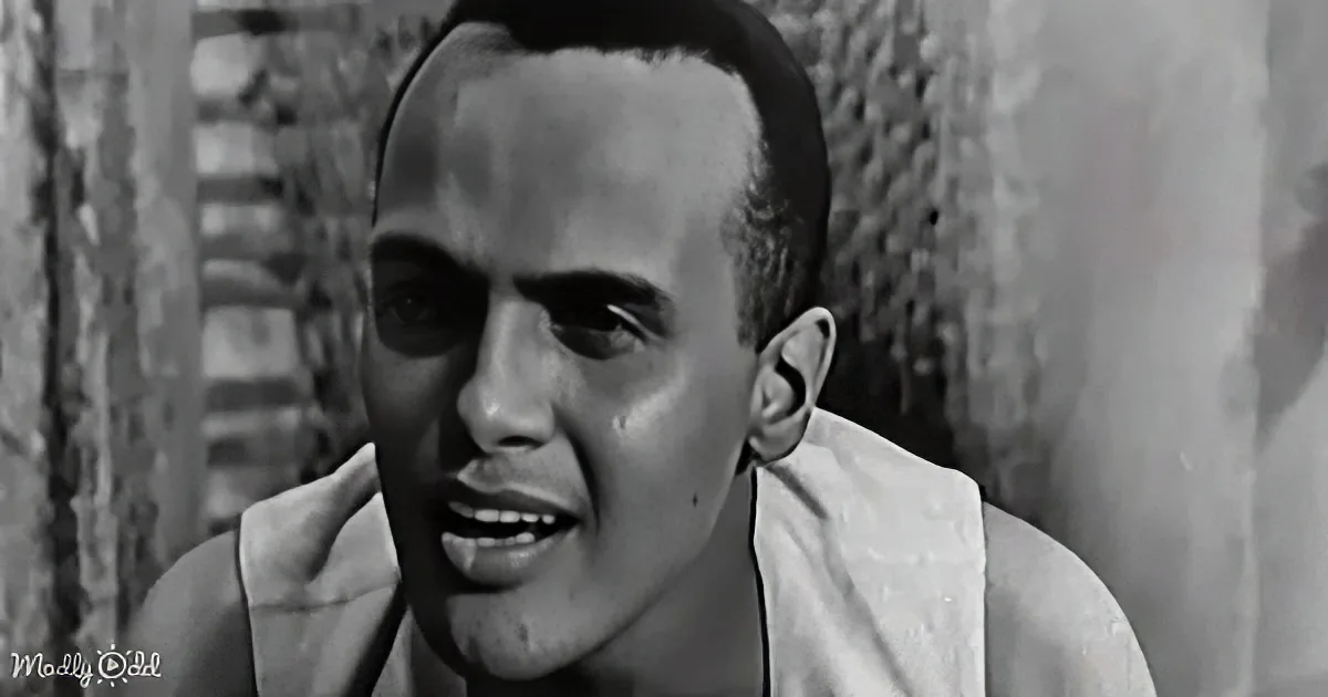 A man with a bald head and a white tank top is shown in a close-up, appearing to speak or react with a serious expression.