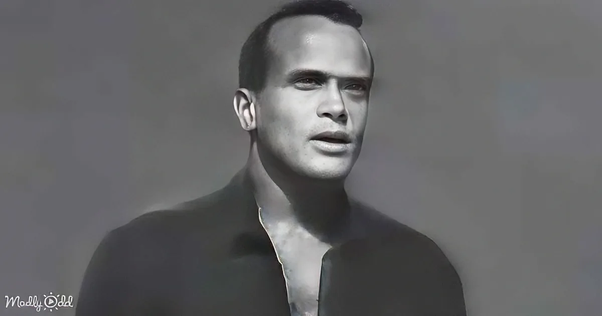 A man in a dark suit with a tie, leaning against a plain background, looking slightly to the side.