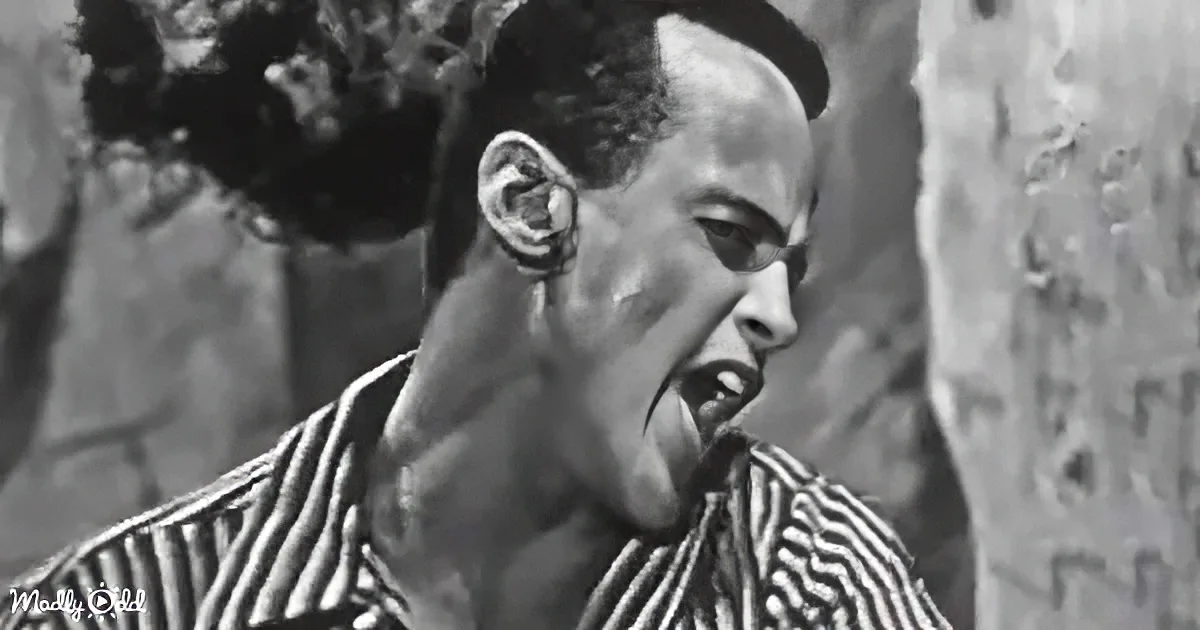 A man in a striped shirt with a distorted face, possibly from a horror movie scene.