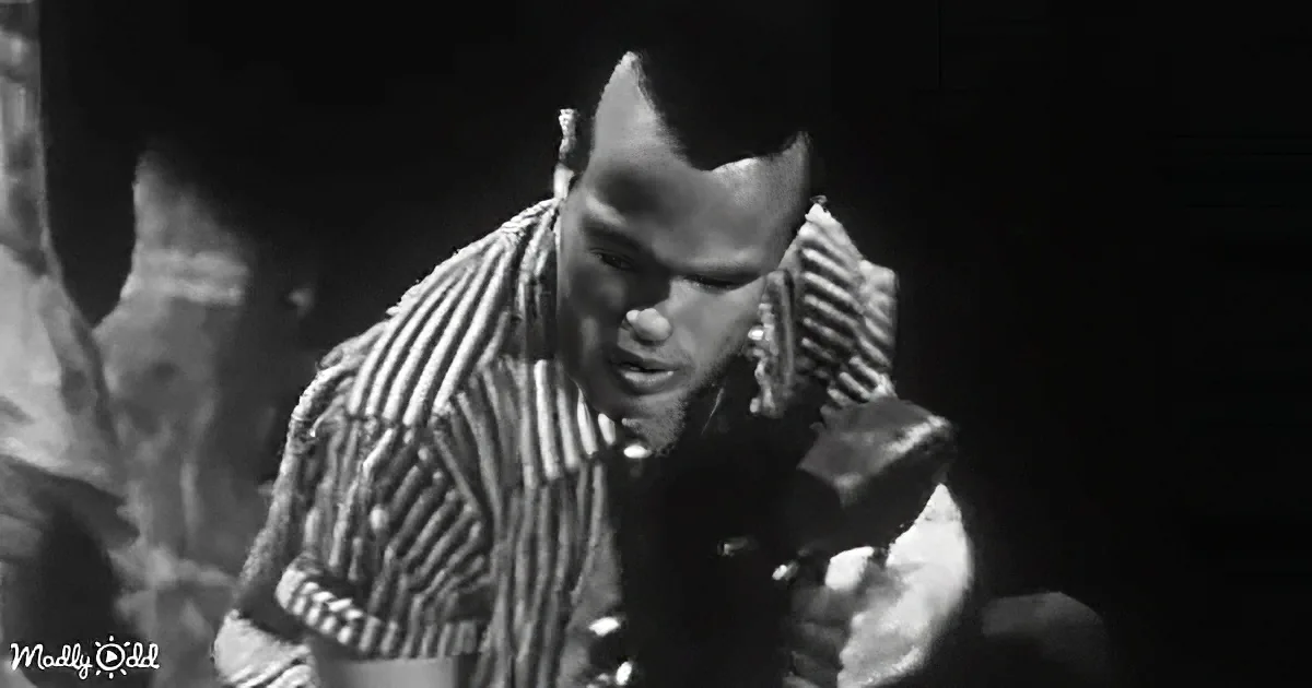 A man in a striped shirt is holding a hammer, looking down, possibly working on something.