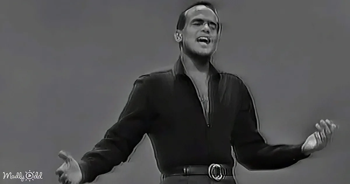 A man in a black shirt with his arms outstretched, singing passionately.
