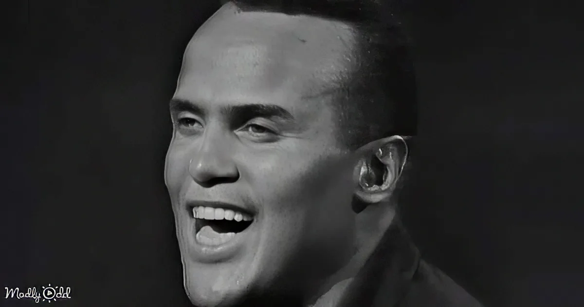 A smiling man with short hair and a dark background, wearing a dark shirt.