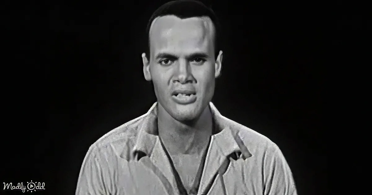 A man in a light-colored shirt with a serious expression, set against a dark background.
