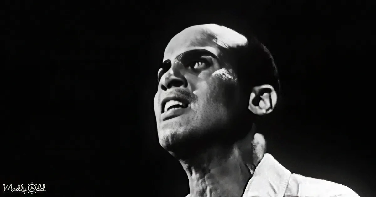 A man in a white shirt looks upward with a serious expression against a dark background.