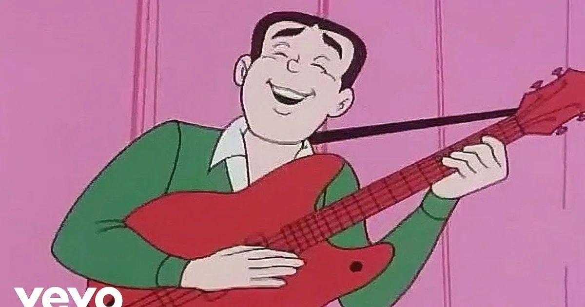 A person with long hair, wearing a suit and tie, singing into a microphone.