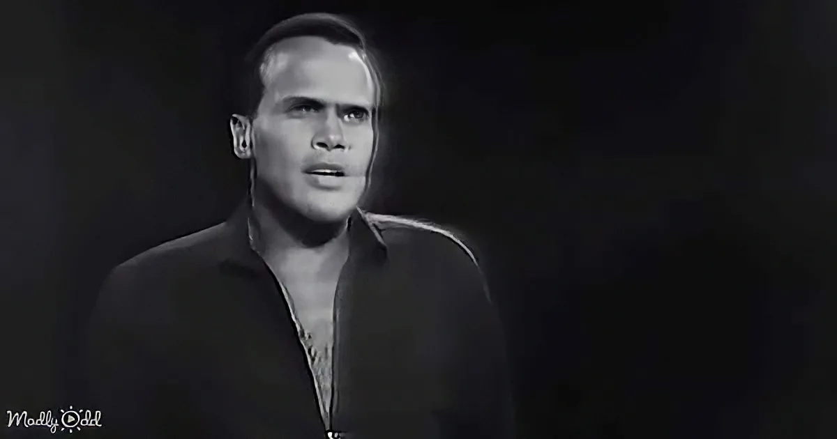 A man in a dark suit with a light background, mouth slightly open, looking to the side.