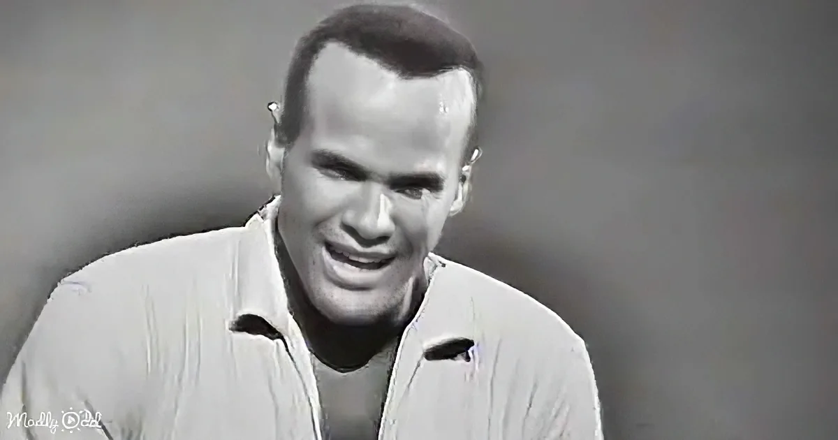 A man in a light-colored shirt smiles, looking slightly to the side, against a plain background.