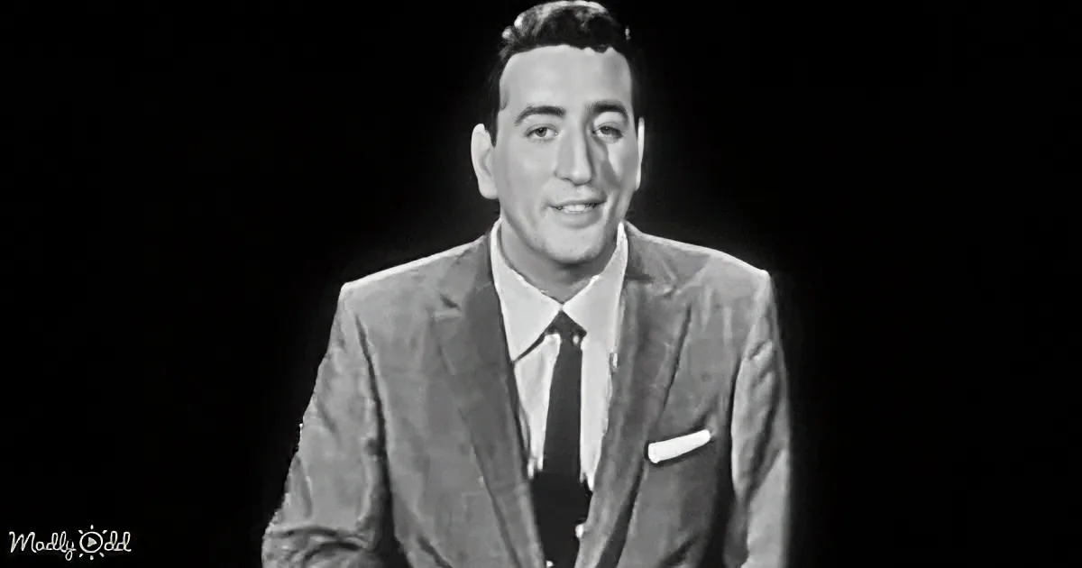 A man in a suit and tie smiles against a dark background.