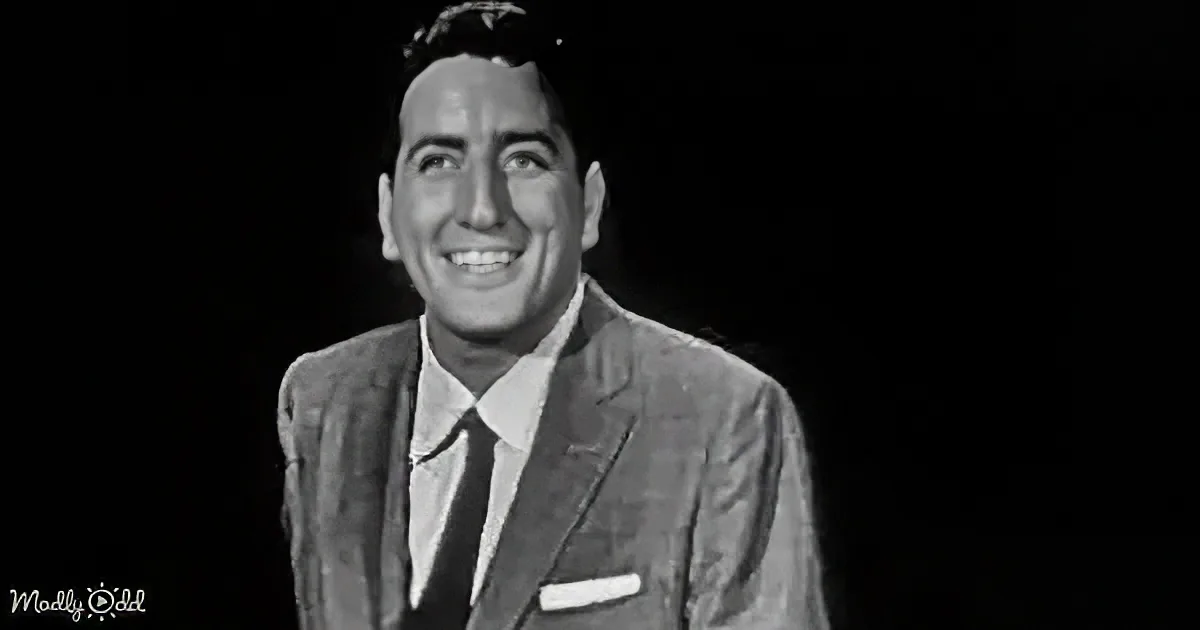 A man in a suit and tie smiles warmly against a dark background.