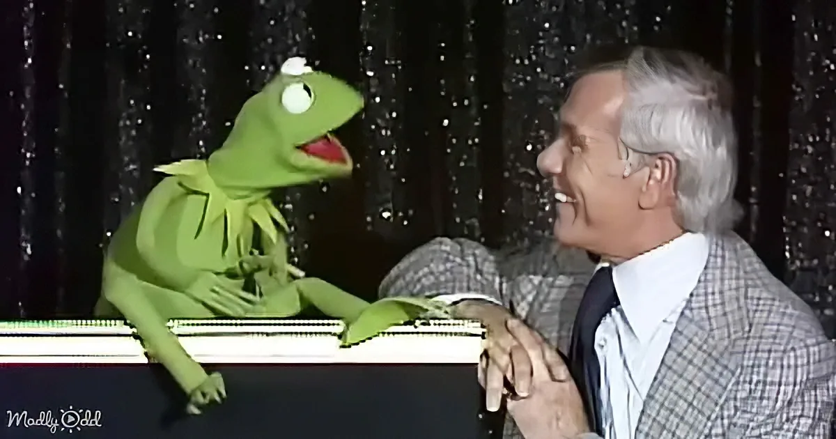 Kermit the Frog sits at a piano, looking up at a smiling man in a suit.