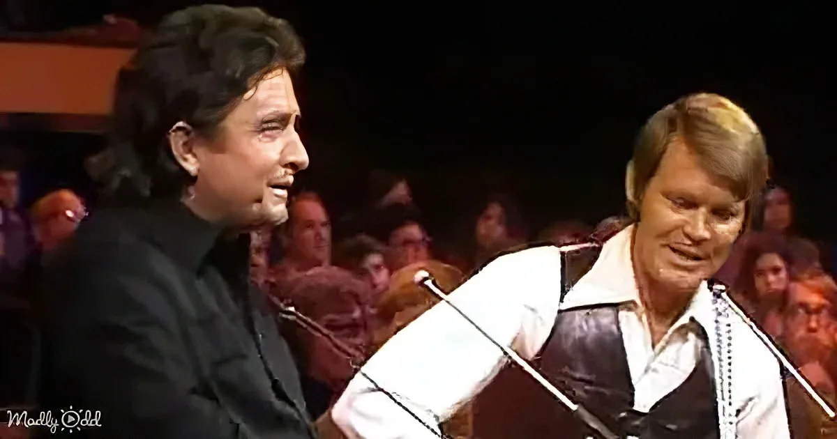 Two men, one playing guitar, the other singing, in front of a live audience.