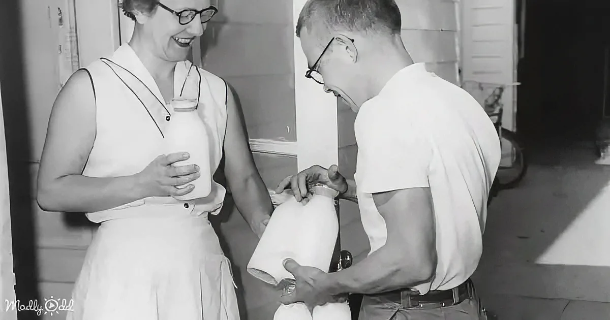 A man and woman are holding and examining a large white object, possibly a container or appliance, in a kitchen setting.