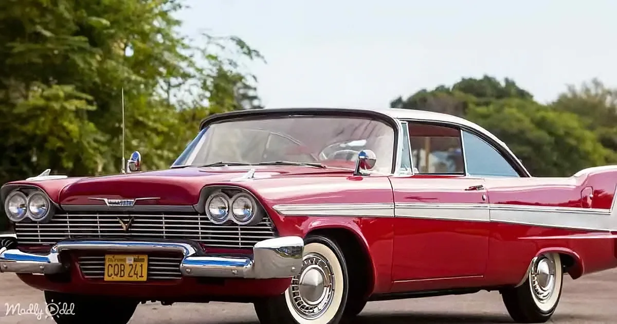 A classic red vintage car with white trim and chrome details is parked outdoors.