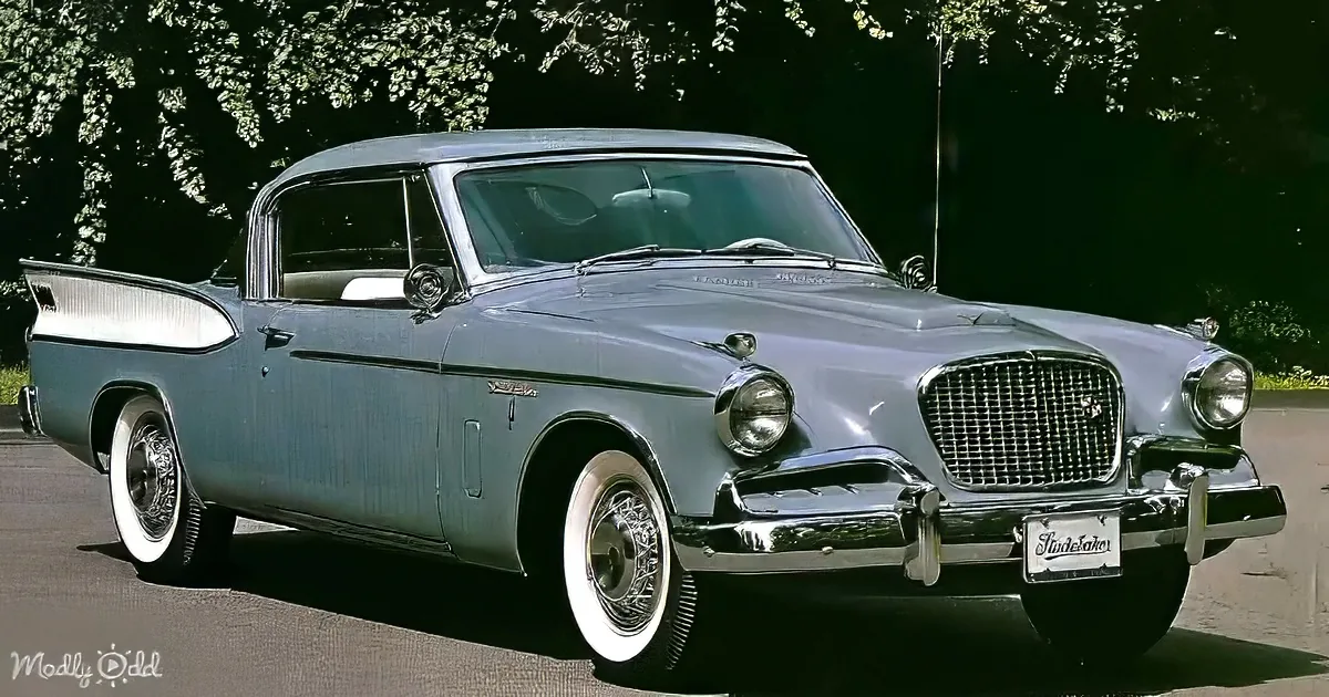 A classic Studebaker car with a sleek design, white wall tires, and a chrome grille is parked on a sunny day.