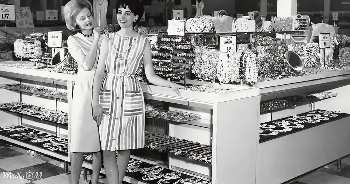 Two women in a jewelry store display, one trying on a necklace, surrounded by various necklaces and bracelets.