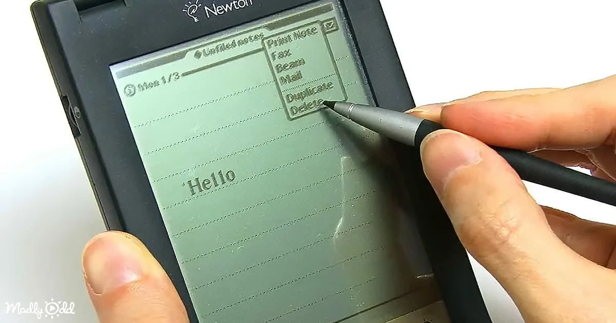 A hand holds a pen, interacting with a Newton PDA displaying a note-taking interface.