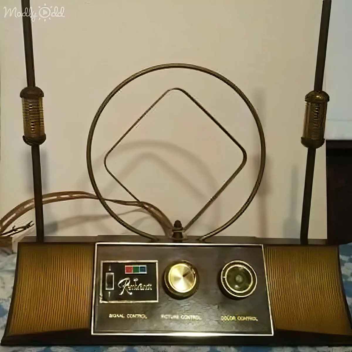 A vintage television set with a large antenna, knobs for signal and picture control, and a color indicator.