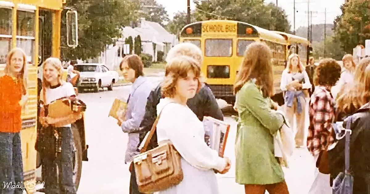 Students board a yellow school bus on a sunny day, carrying books and backpacks.