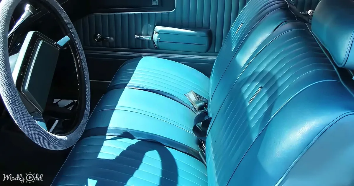 Turquoise leather seats and steering wheel in a vintage car interior.