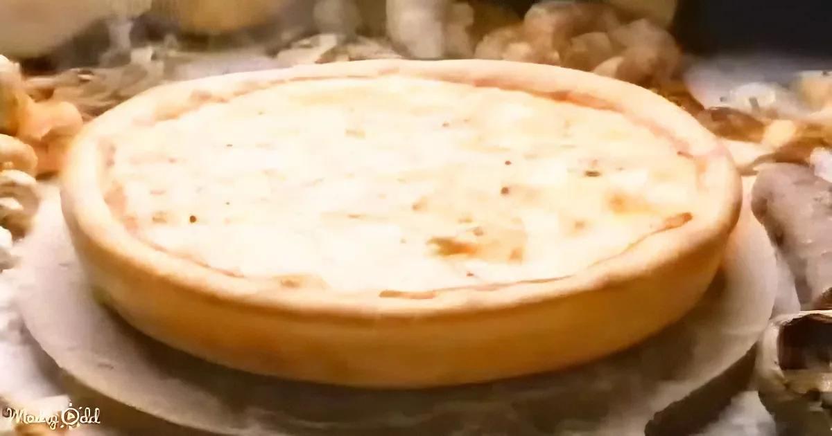 A golden-brown pie with a flaky crust sits on parchment paper, surrounded by blurred ingredients.