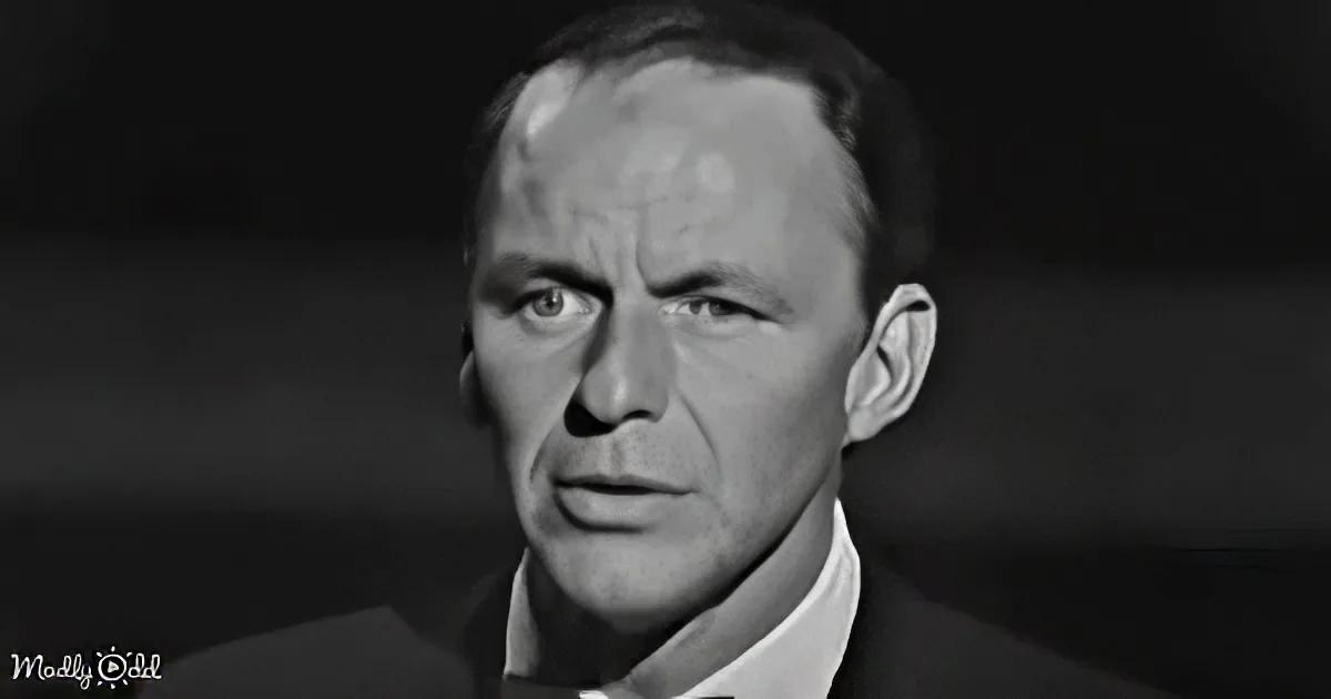 A man in a suit and tie, looking serious, with a dark background.