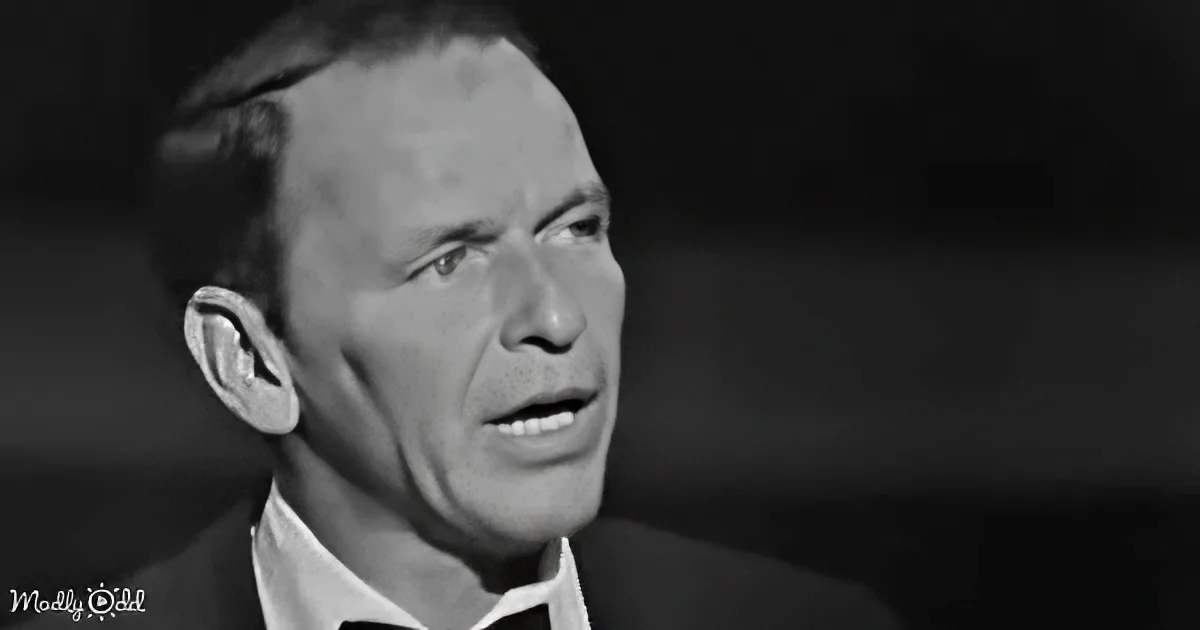 A man in a suit and tie, looking upwards with a serious expression, in a black-and-white image.