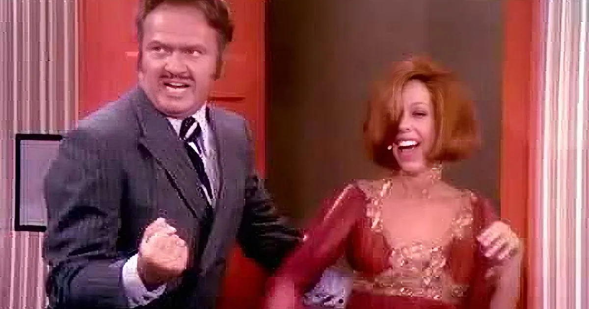 A man in a suit and a woman in a red dress are smiling and laughing together.