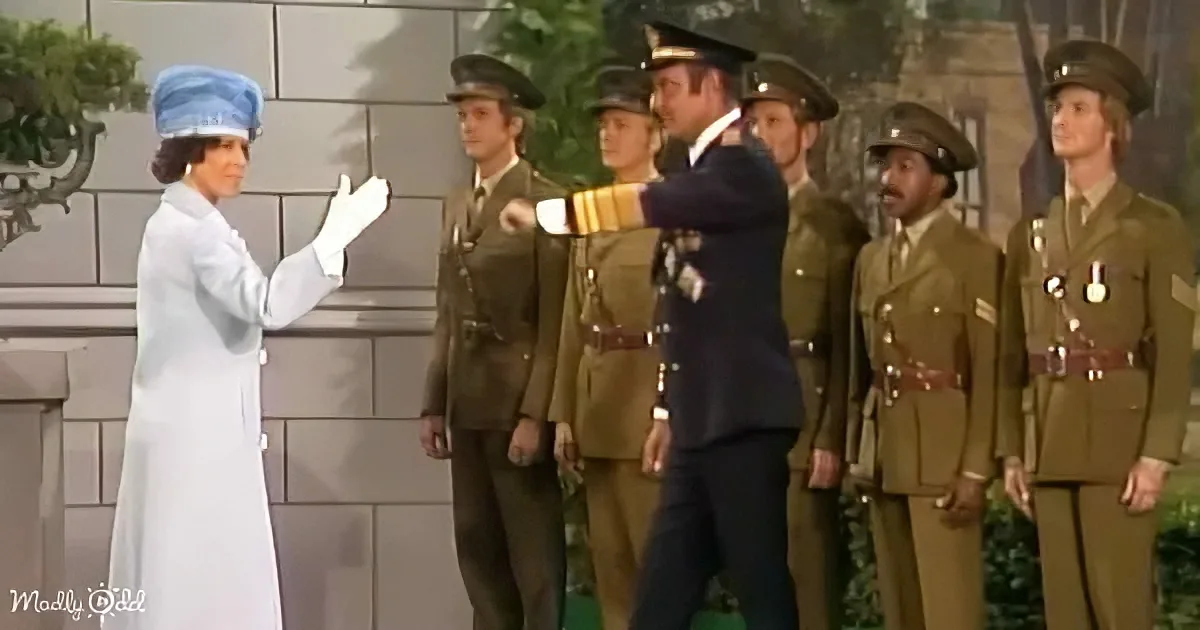 A woman in a white outfit and blue hat gestures to a group of uniformed soldiers.
