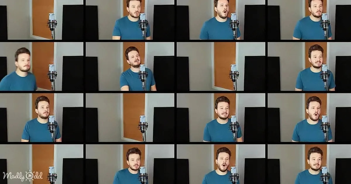 A man in a blue shirt sings into a microphone in a recording studio setup.