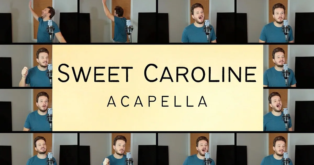 A man in a teal shirt sings into a microphone in a room with a wooden panel and black frames.